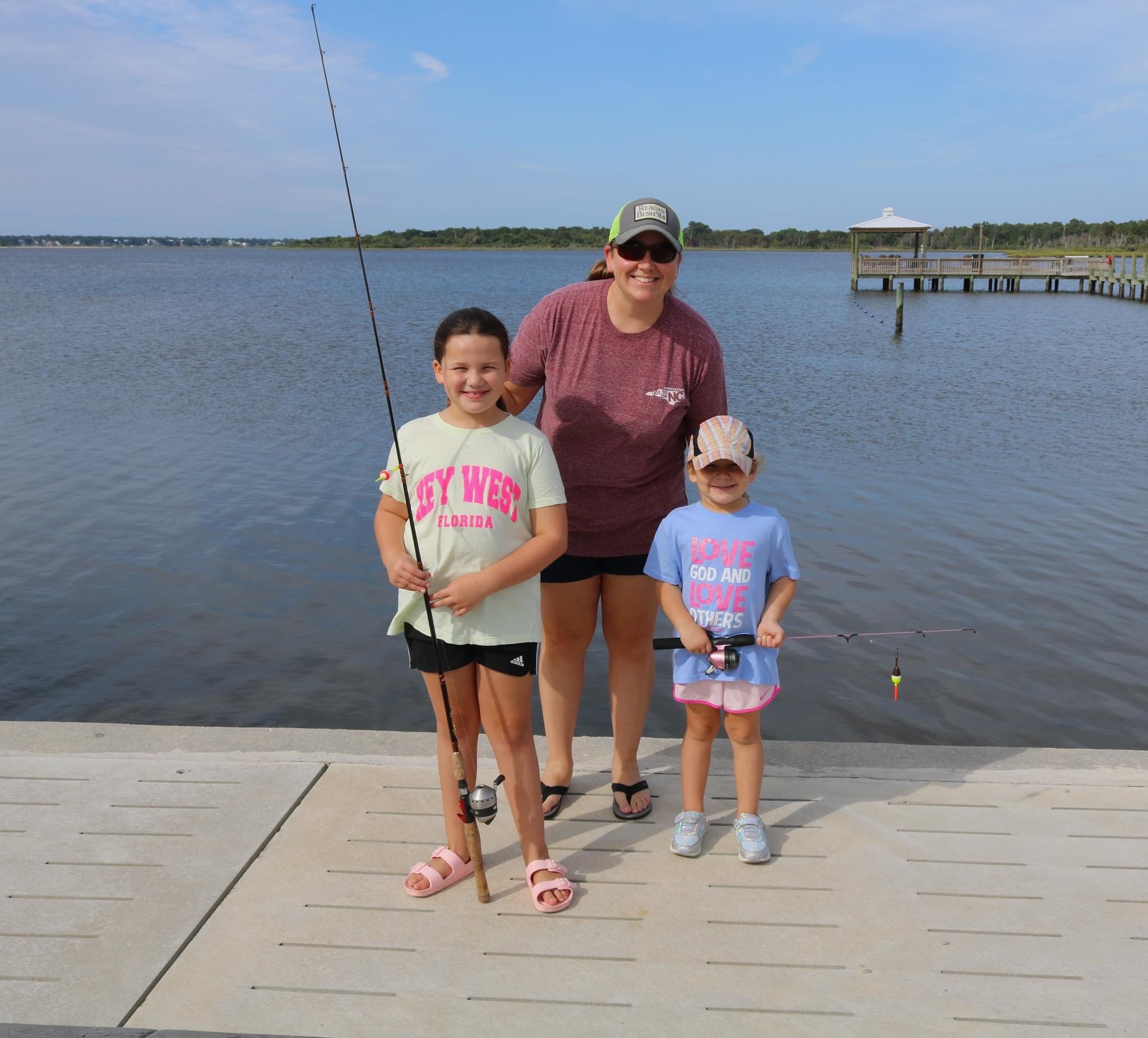 Three girls fishing on a dock.