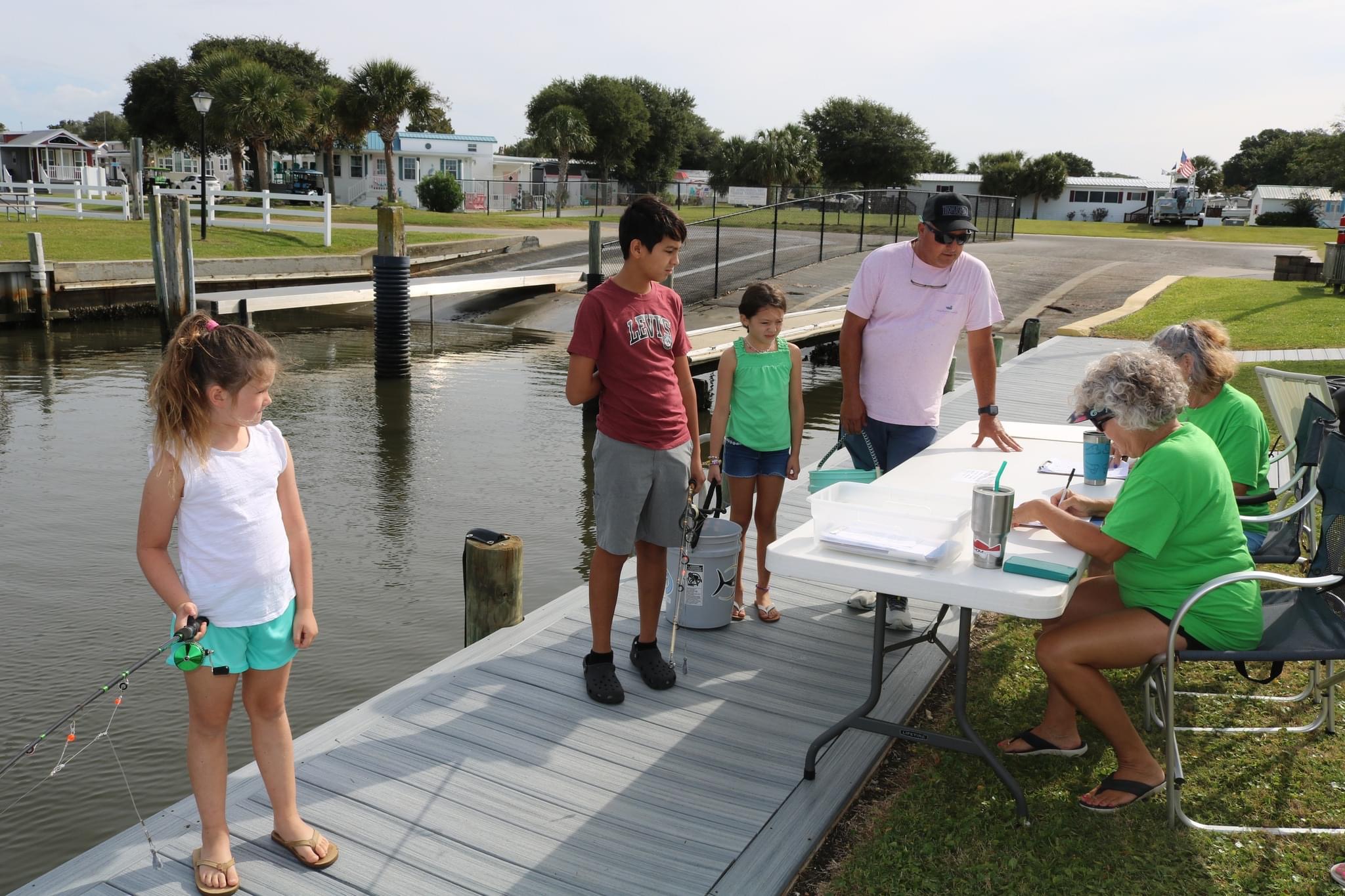 Family fishing on a dock by the water.