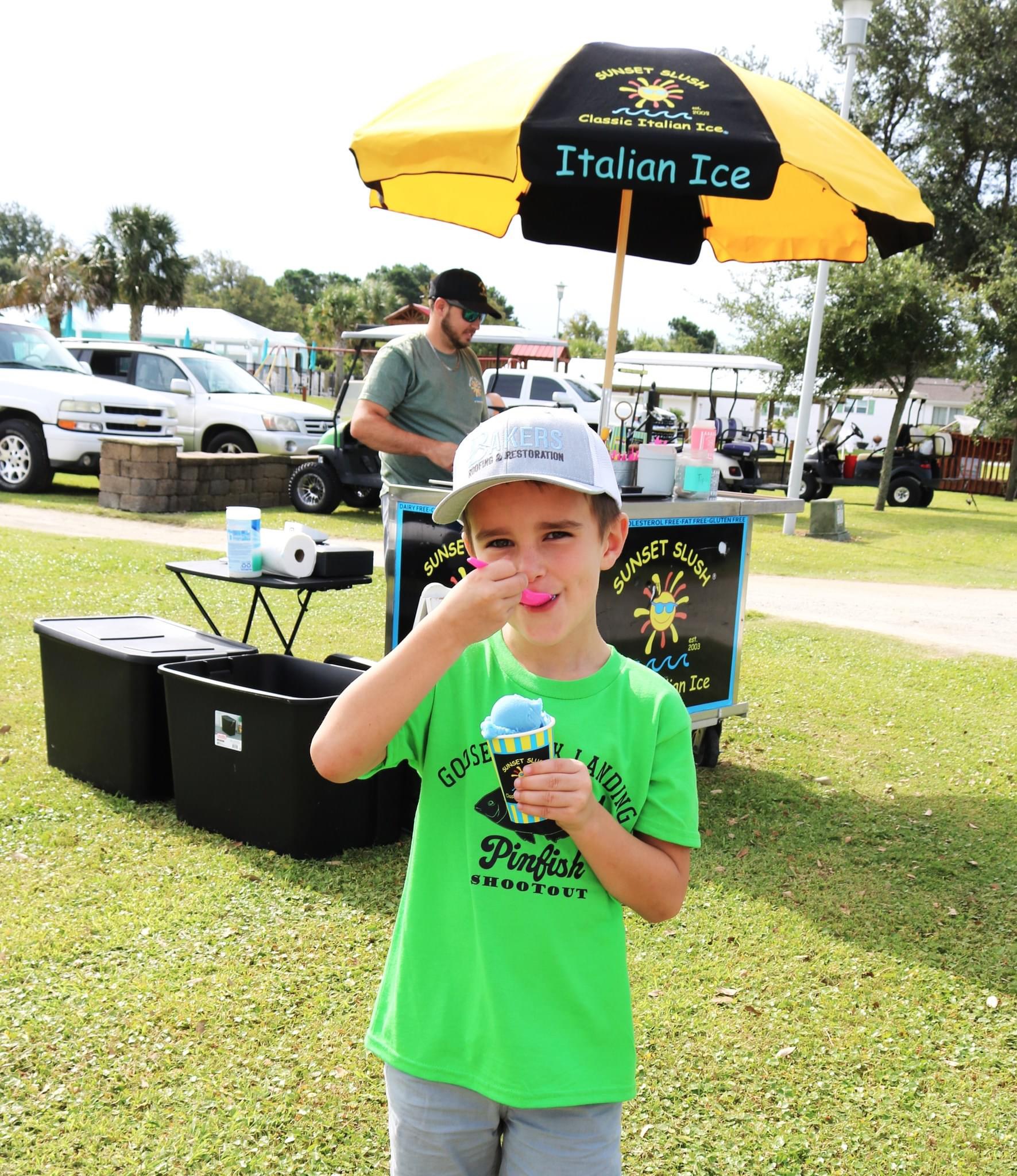 Boy enjoying Italian ice under a yellow umbrella.