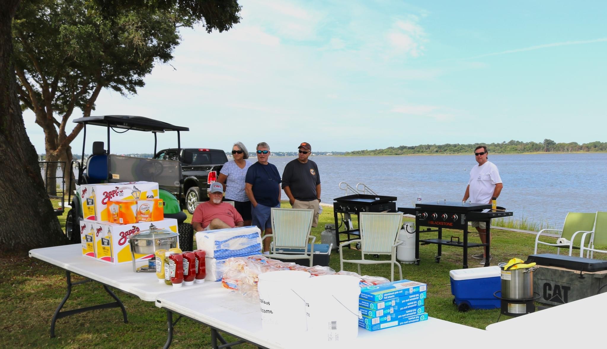 Group of people grilling by the water.