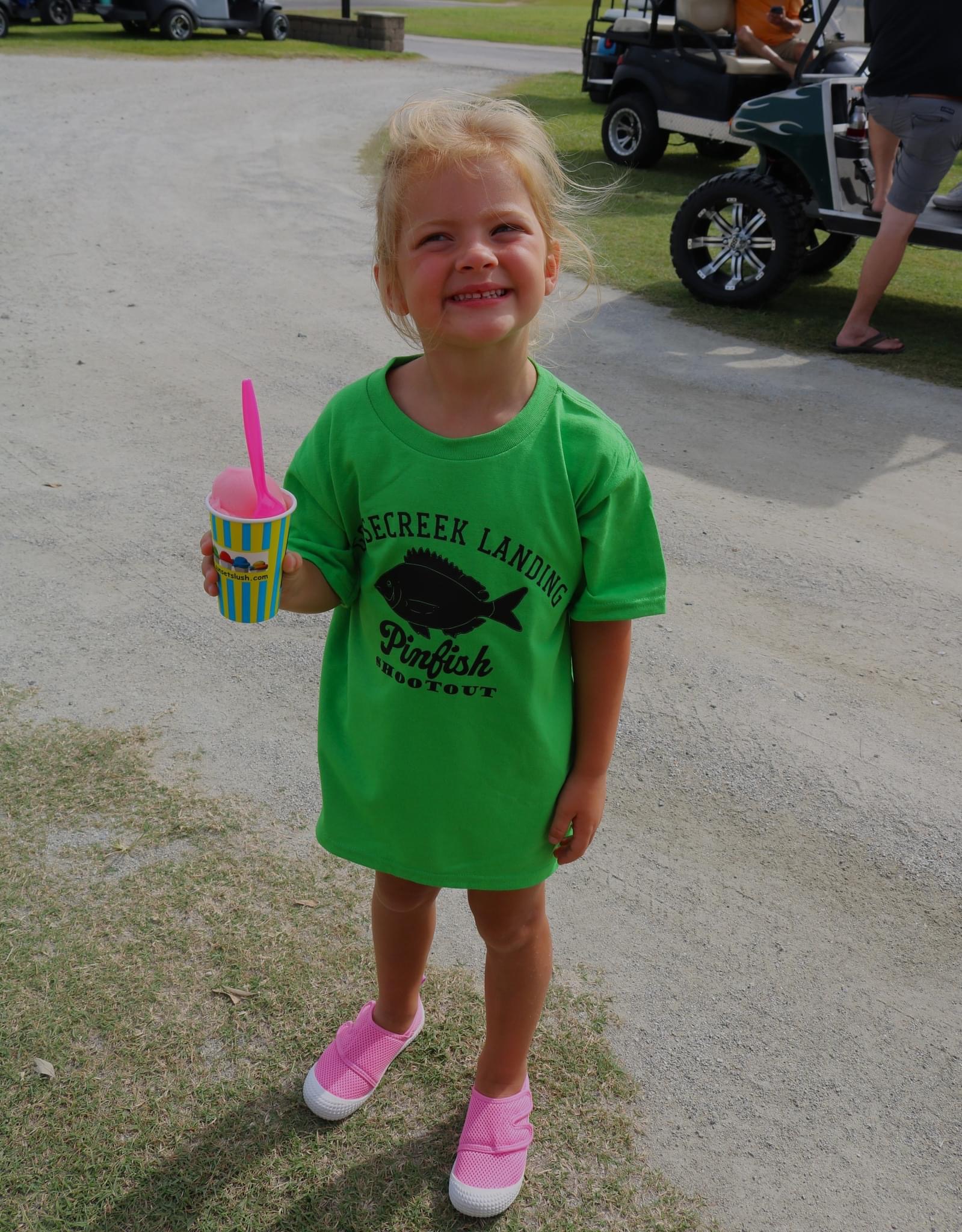 Girl in green shirt holding a snow cone.