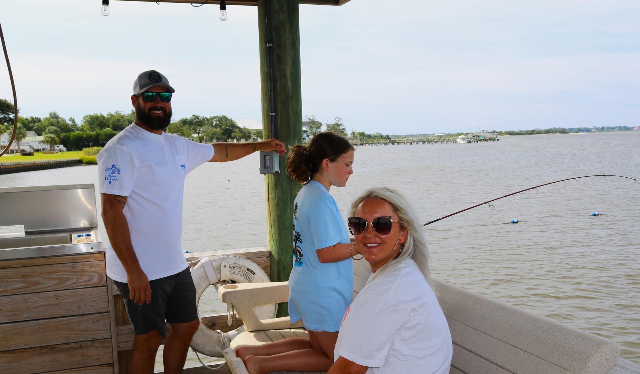 Family fishing from a pier on a sunny day.