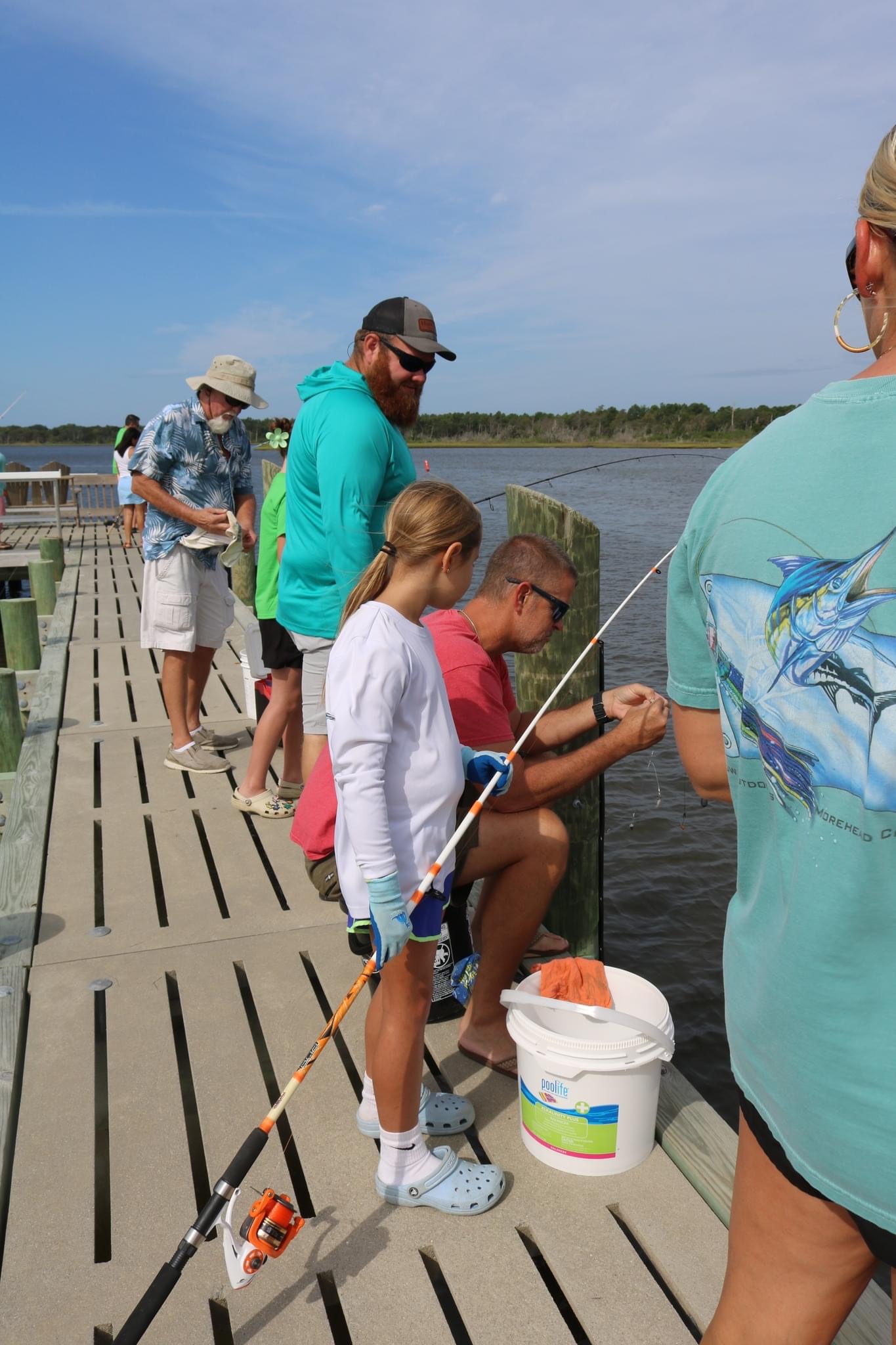 Family fishing on a wooden dock.
