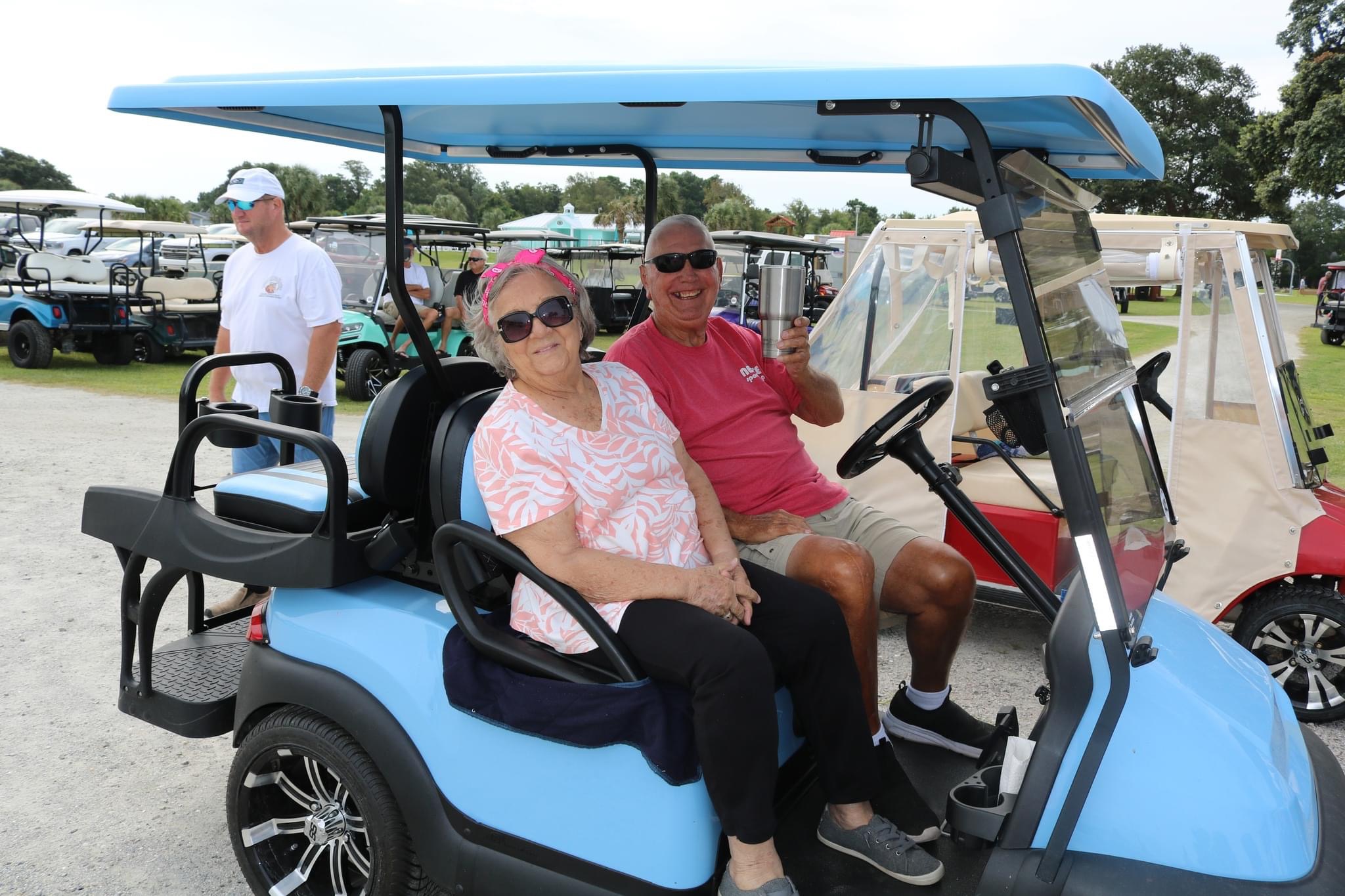 Couple riding in blue golf cart.