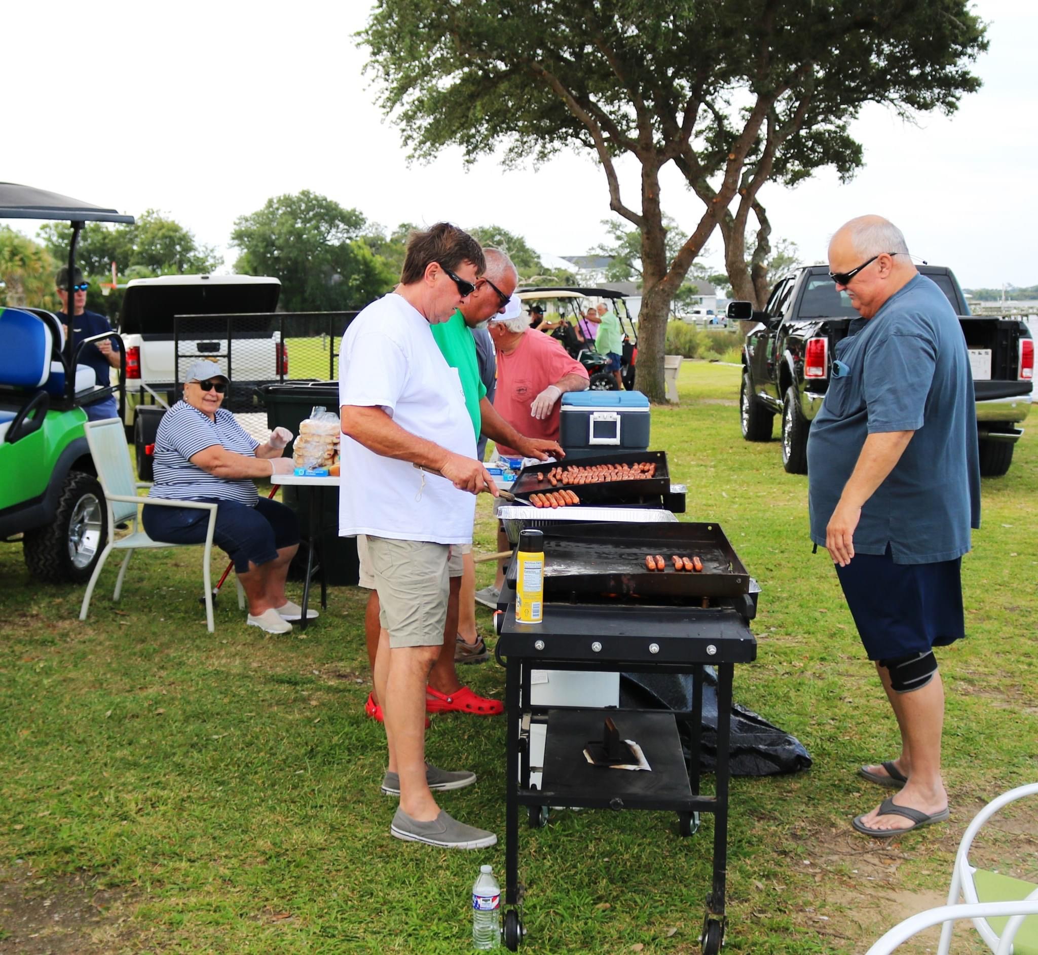 Men grilling hot dogs outdoors.